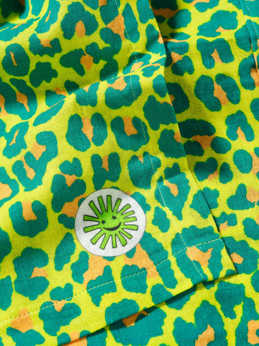 close up of large green leopard print baby muslin cloth folded with corner detail - premium quality cotton by sunny and moon baby gift set luxury stylish cool